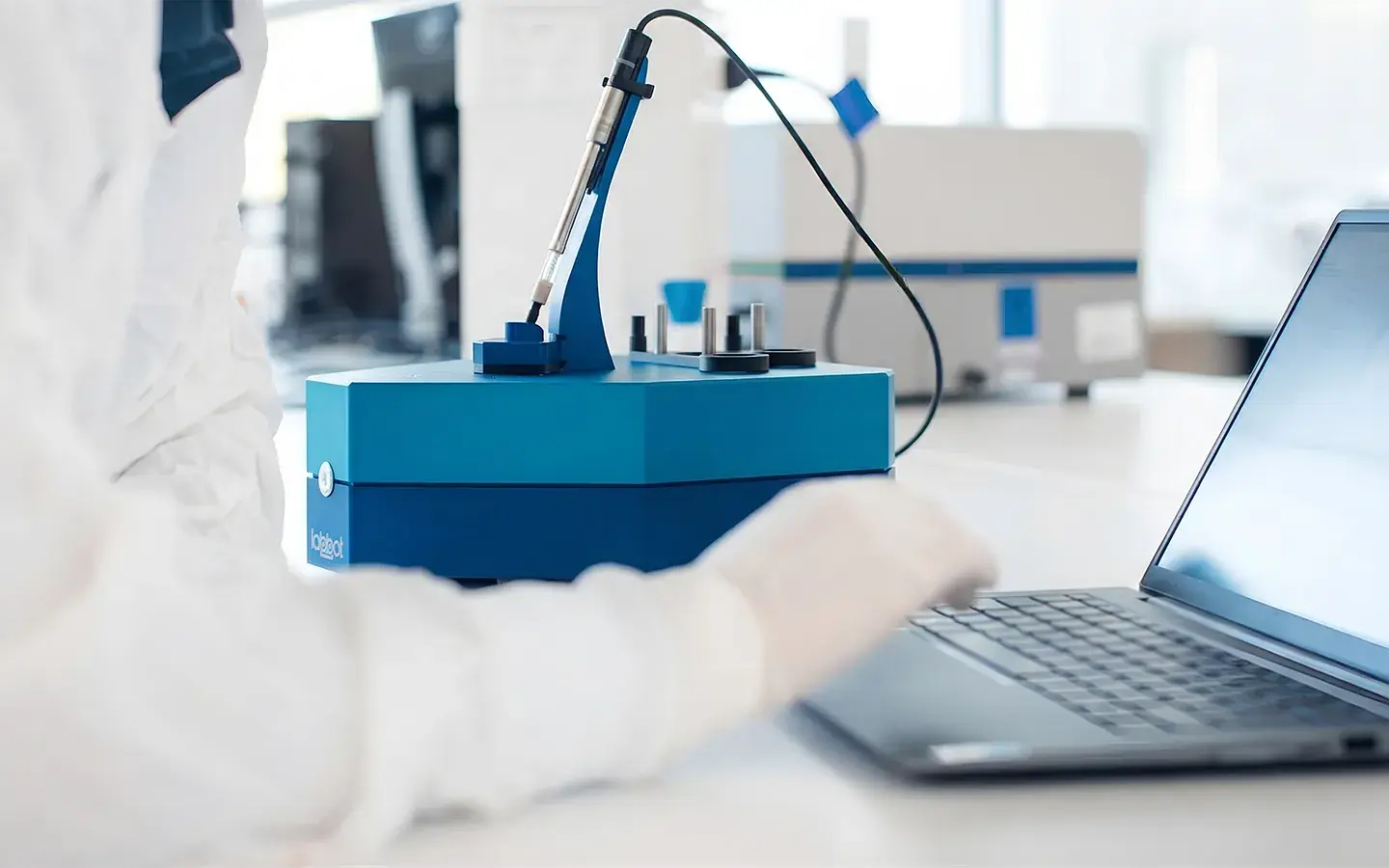 A scientist at the Labbot instrument, working at a laptop beside it